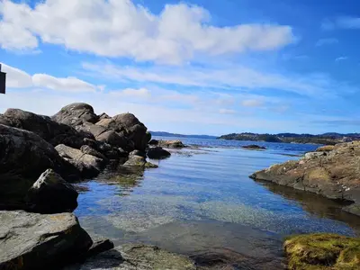 a body of water with rocks on the shore at Cozy house in historical area in Bergen