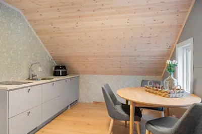 a kitchen with a wooden ceiling and a table and chairs at Jordeplegarden Apartments in Tønjum
