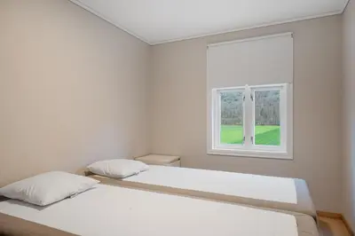 two beds in a white room with a window at Jordeplegarden Apartments in Tønjum