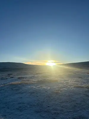 a sun setting in the middle of a snow covered field at Mountain Lodge - Midtgardstunet in Ringebu