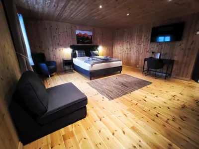 a bedroom with a bed and a chair and a couch at Mountain Lodge - Midtgardstunet in Ringebu