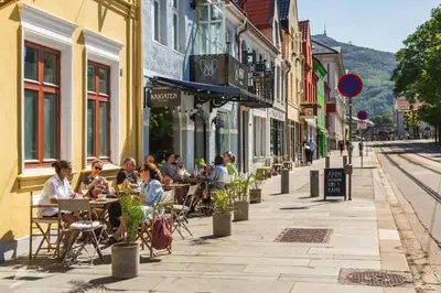 a group of people sitting at tables on a city street at The 1880 Authentic Bergen Dream I 500m to Bryggen in Bergen