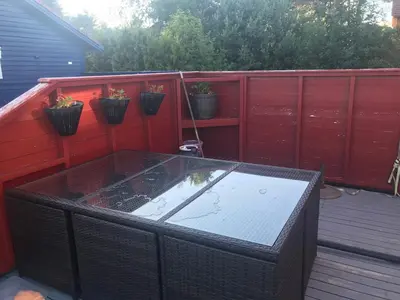 a hot tub on a deck with a red wall at Townhouse with 4 bedrooms near Sørstrand