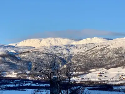a snow covered mountain with a town in the foreground at Familiehytte med fantastisk beliggenhet i Vestlia in Geilo