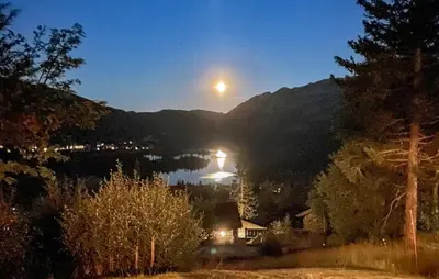 a full moon rising over a lake at night at 4 Bedroom Gorgeous Home In Rjukan in Rjukan
