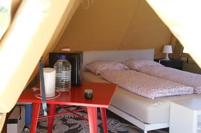 a bed in a tent with a red table at Alpakkaparken Glamping med parktilgang