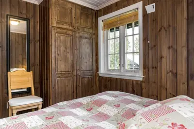 a bedroom with wooden walls and a bed and a window at Fjellkos, mountain cabin in Gol in Gol