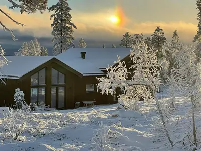 a house covered in snow with the sun in the background at Trysilfjell hytteområde 2115 by Vacation Trysil in Trysil