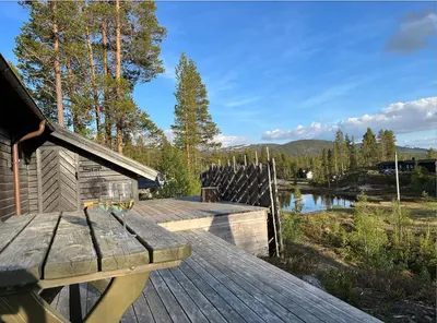 a wooden deck with a bench next to a lake at Cozy family cabin at Hovden in Bykle