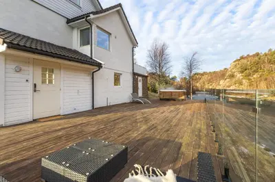 a backyard with a wooden deck and a house at Aurora Bliss - Waterfront Jacuzzi & Sauna near Bergen in Askøy