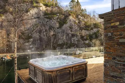 a jacuzzi tub sitting on a deck next to a mountain at Aurora Bliss - Waterfront Jacuzzi & Sauna near Bergen in Askøy
