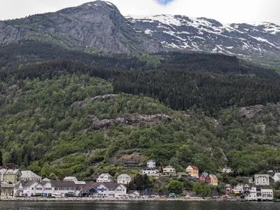 a town on the shore of a lake with a mountain at Cozy bedroom & basement with amenities in Odda