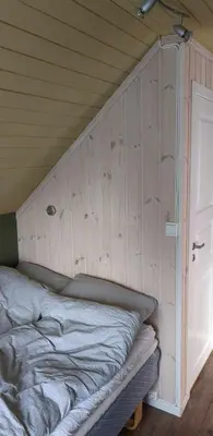 a bed in a room with a wooden wall at Cozy bedroom & basement with amenities in Odda