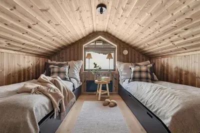 two beds in a room with a wooden ceiling at Large family cabin at Hafjell with ski in-ski out in Hafjell