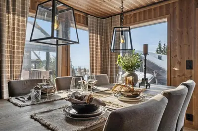 a dining room with a wooden table with chairs and a dining room tableablishbestos at Large family cabin at Hafjell with ski in-ski out in Hafjell