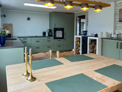 a kitchen with a wooden table and a kitchen with green cabinets at Family Cabin By Lake Mylla With Private Dock in Lunner