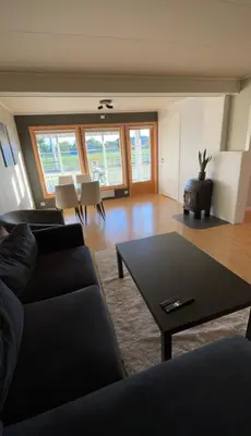 a living room with a black couch and a table at Sentral og romslig leilighet på Levanger in Levanger