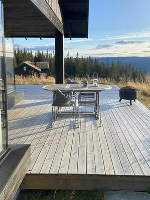 a patio with a table and chairs on a deck at Mountain Cabinin Valdres in Aurdal