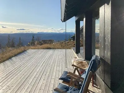 a wooden deck with a rocking chair on a house at Mountain Cabinin Valdres in Aurdal