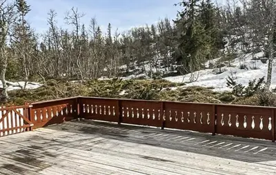 a wooden deck with a wooden fence on a snowy hill at Cabin With Terrace And Mountain Views In Tuddal in Tuddal
