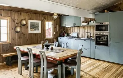 a kitchen with a wooden table and chairs and a wooden floor at Cabin With Terrace And Mountain Views In Tuddal in Tuddal