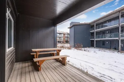 a wooden bench sitting on a deck with a building at Geilo Town Centre - Apartment with a Superb Location and walking Distance to Everything in Geilo