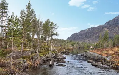 a river in the middle of a mountain with trees at Amazing Home In Skare With Sauna in Skare