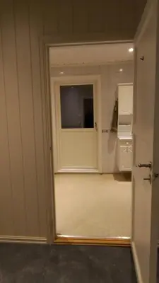 a room with a door and a kitchen with a refrigerator at Skap Opplevelser! in Svingvoll