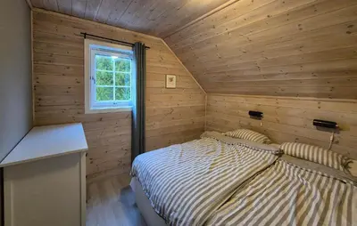 a bedroom with a bed in a wooden wall at Beautiful Home In Bøvågen With Sauna in Bøvågen