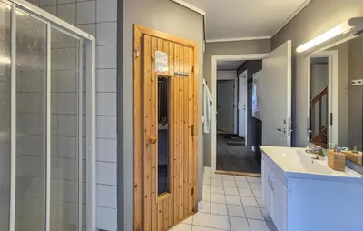 a bathroom with a sink and a wooden door at Beautiful Home In Bøvågen With Sauna in Bøvågen