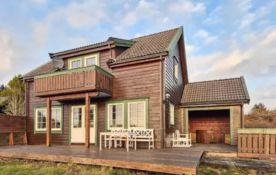 a house with a deck with a table and chairs at Beautiful Home In Bøvågen With Sauna in Bøvågen
