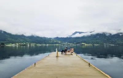 two people sitting on a dock on a lake at 3 Bedroom Awesome Home In Strandebarm in Strandebarm