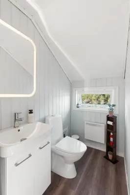 a white bathroom with a toilet and a sink at Furiholmen in Askøy