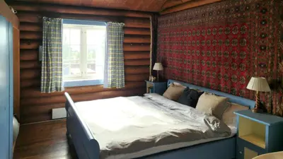 a bedroom with a bed in a room with wooden walls at Historic Cabin From 1906 In Sjusjøen in Sjusjøen