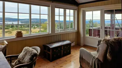 a room with chairs and windows with a view at Historic Cabin From 1906 In Sjusjøen in Sjusjøen