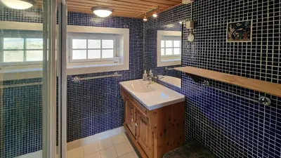 a blue tiled bathroom with a sink and a shower at Historic Cabin From 1906 In Sjusjøen in Sjusjøen