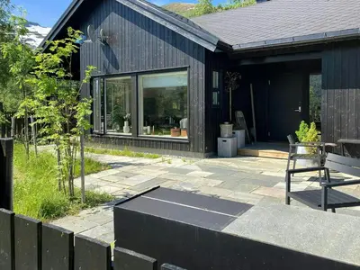 a black house with a bench on a patio at Charming Mountain Cabin In Spectacular Nature in Brunstad