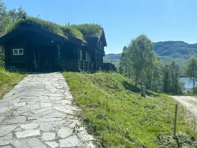 a building with a grass roof next to a road at Log Cabin By Hardangervidda National Park in Nesland