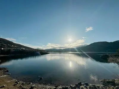 a lake with the sun shining on the water at Log Cabin By Hardangervidda National Park in Nesland