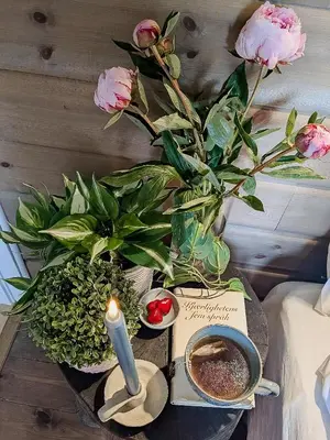 a table with a candle and flowers and a book at Modern Hand-Crafted Log Cabin in Dovreskogen