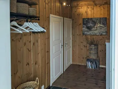 a hallway with wood paneling and a door and shoes at Modern Hand-Crafted Log Cabin in Dovreskogen