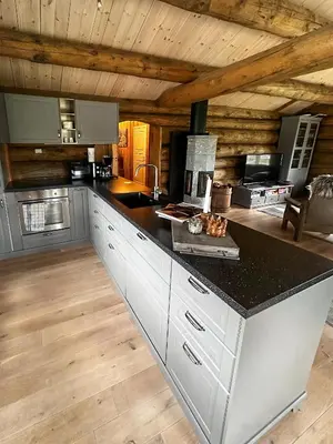 a kitchen with white cabinets and a black counter top at Modern Hand-Crafted Log Cabin in Dovreskogen