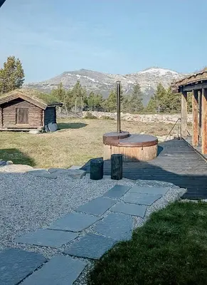 a stone walkway leading to a building with mountains in the background at Modern Hand-Crafted Log Cabin in Dovreskogen
