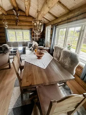 a dining room with a wooden table and chairs at Modern Hand-Crafted Log Cabin in Dovreskogen