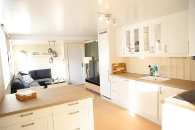 a kitchen with white cabinets and a living room at Central apartment in Lillehammer in Lillehammer