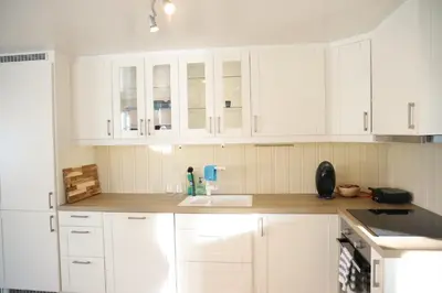 a white kitchen with white cabinets and a sink at Central apartment in Lillehammer in Lillehammer