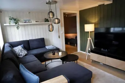a living room with a blue couch and a piano at Central apartment in Lillehammer in Lillehammer