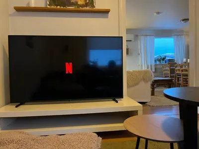 a large flat screen tv sitting on a stand in a living room at Panoramic mountain views, space for the whole family in Vossevangen
