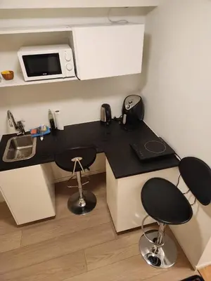 a small kitchen with a black counter and two stools at Nice Apartment in Sjetnemarka - Free parking and WiFi in Trondheim