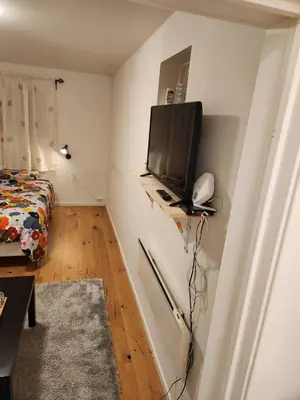 a small room with a tv on a wall at Nice Apartment in Sjetnemarka - Free parking and WiFi in Trondheim